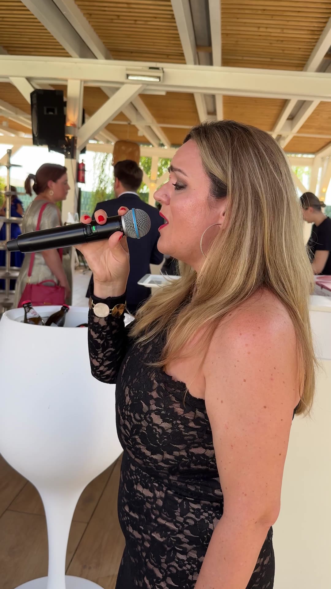 Alesya singt mit Mikrofon bei einer Hochzeit im Grünen