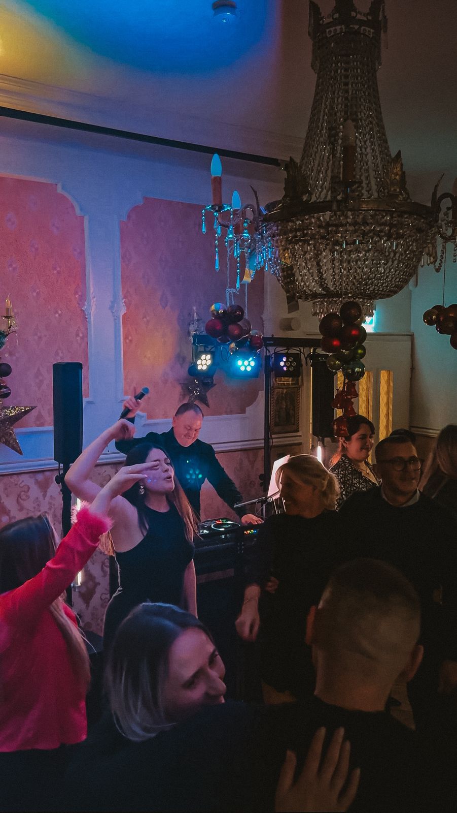 Volle Tanzfläche unter Kronleuchtern, im Vordergrund das DJ-Pult